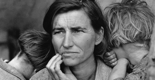 Picture of woman with two small children burying their faces in her neck. Woman looks sad and hopeless.